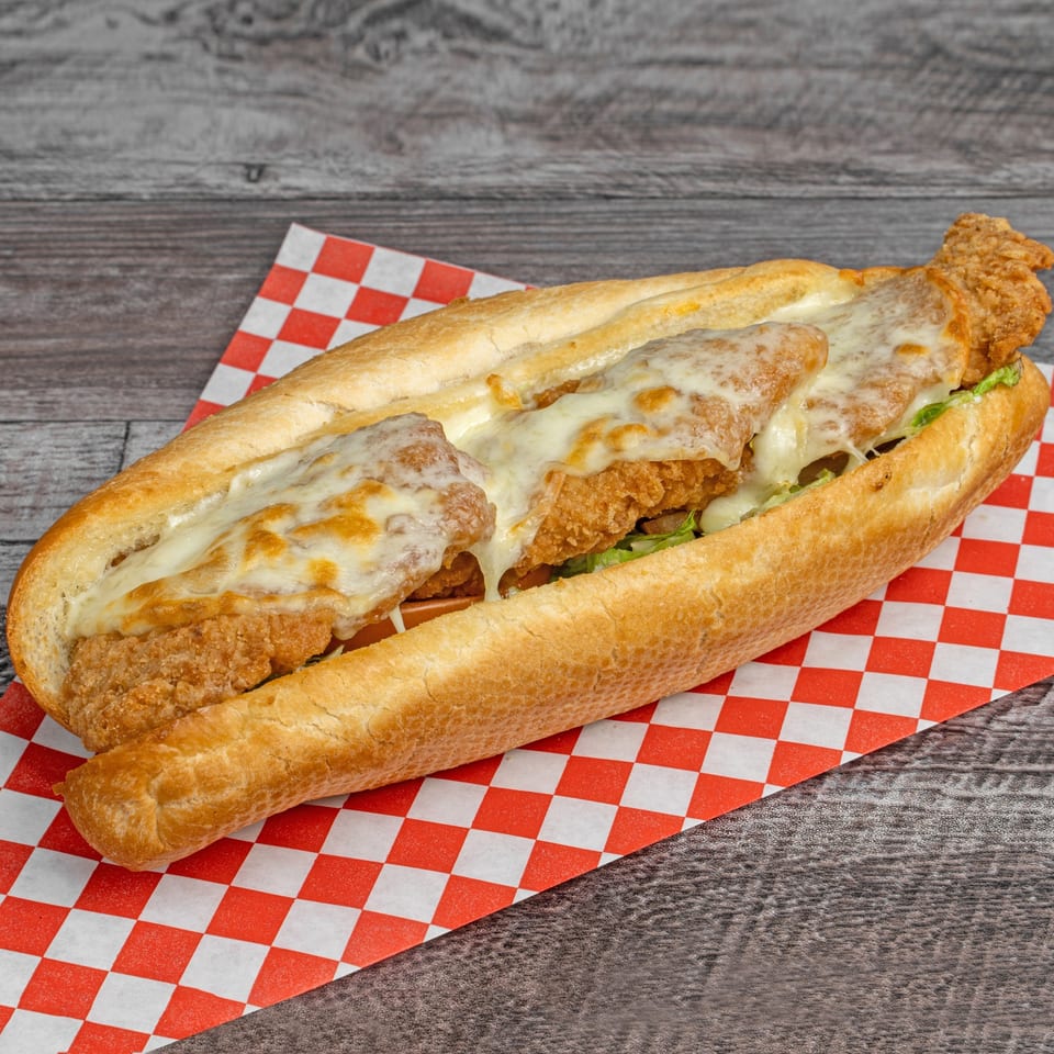 A crispy fried chicken sandwich with melted cheese and lettuce on a sub roll.