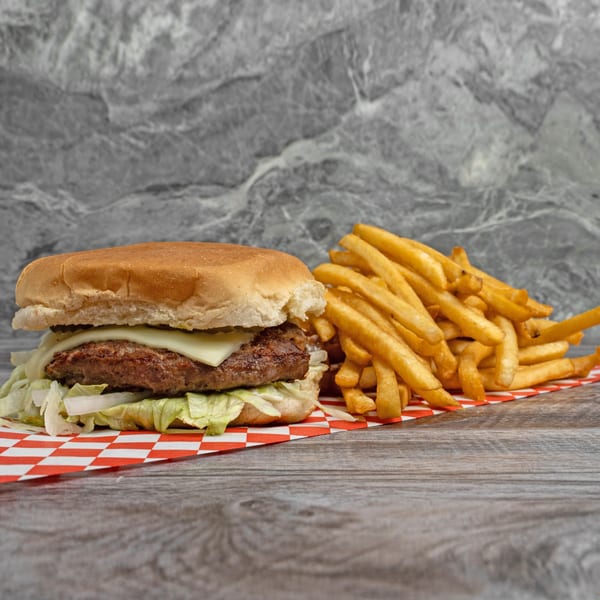 Cheeseburger with lettuce and onions, served with a side of golden french fries on a checkered paper.