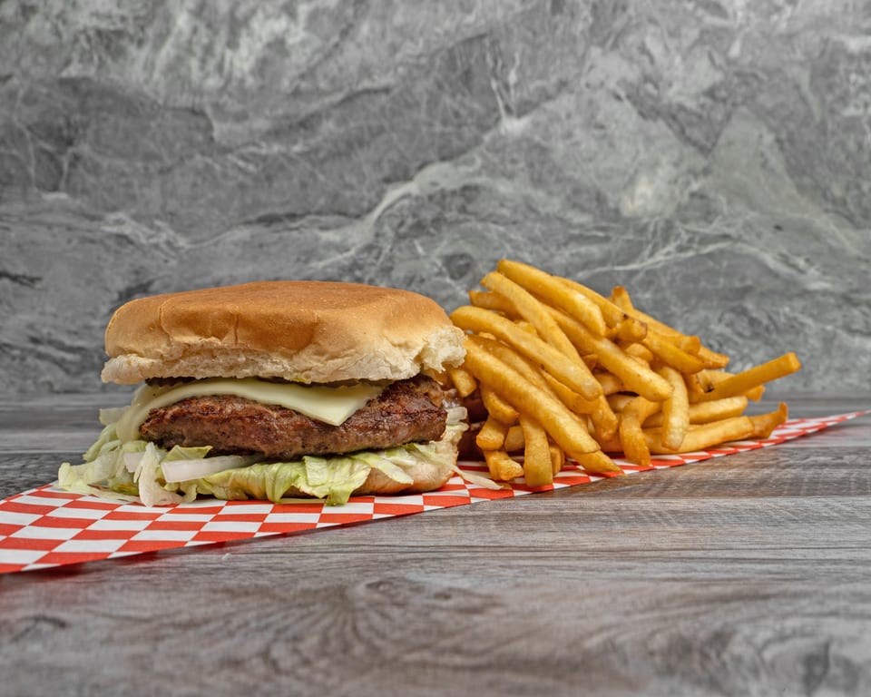 Cheeseburger with lettuce and onions, served with a side of golden french fries on a checkered paper.