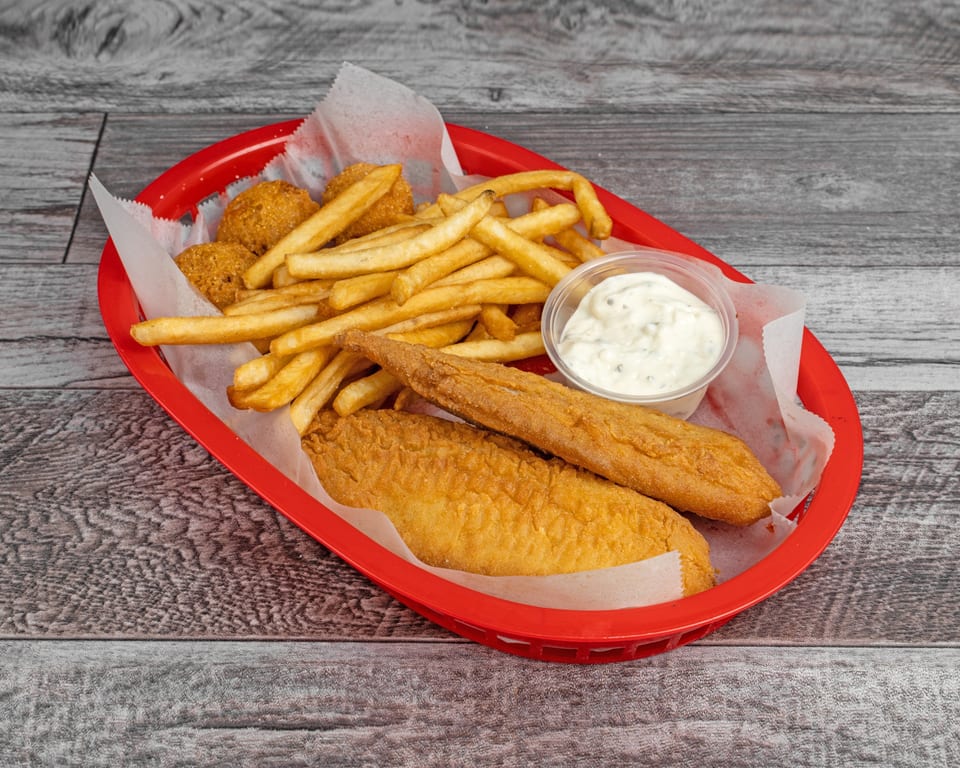 Fried fish fillets, hush puppies, and french fries with tartar sauce in a red basket.