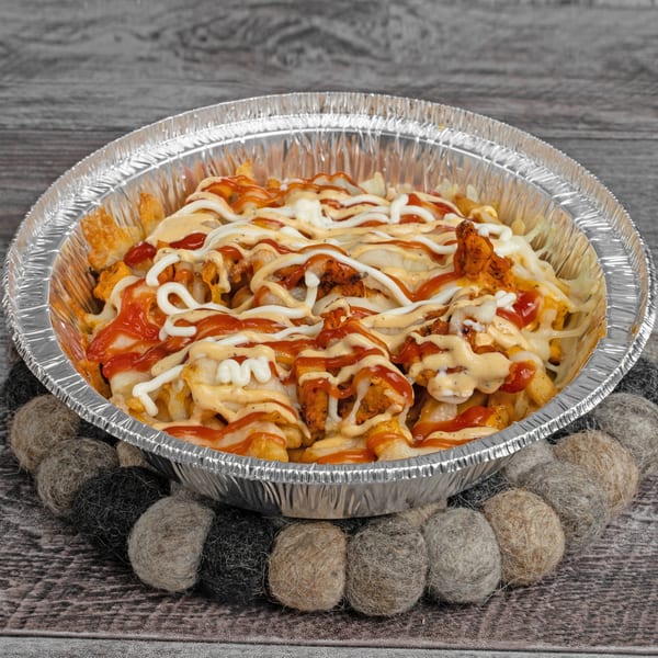 Fries topped with chicken, cheese, ketchup, and white and orange sauces in a foil container.