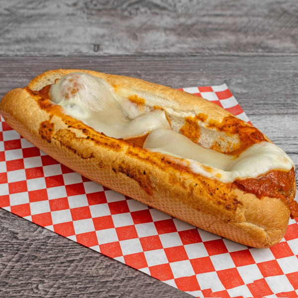 Meatball sub with melted mozzarella cheese and marinara sauce on a red and white checkered paper.