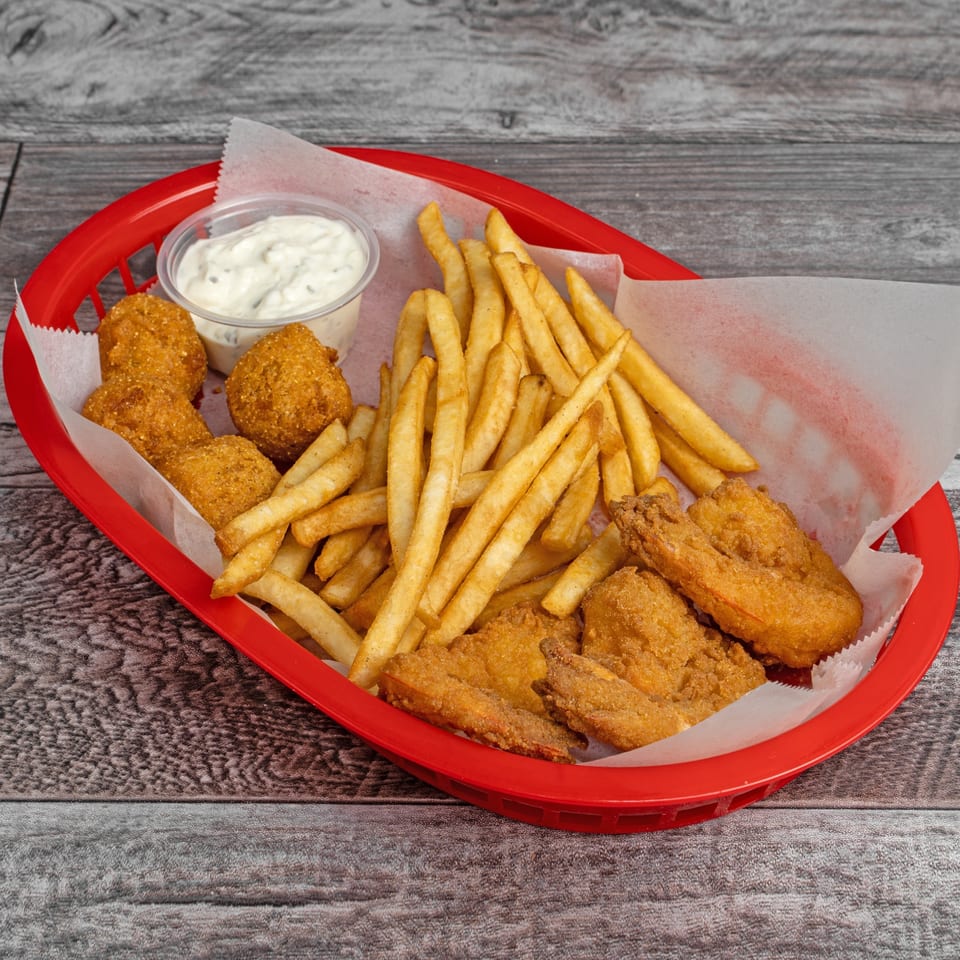 A red basket filled with golden-brown fried fish, hush puppies, french fries, and a side of tartar sauce.